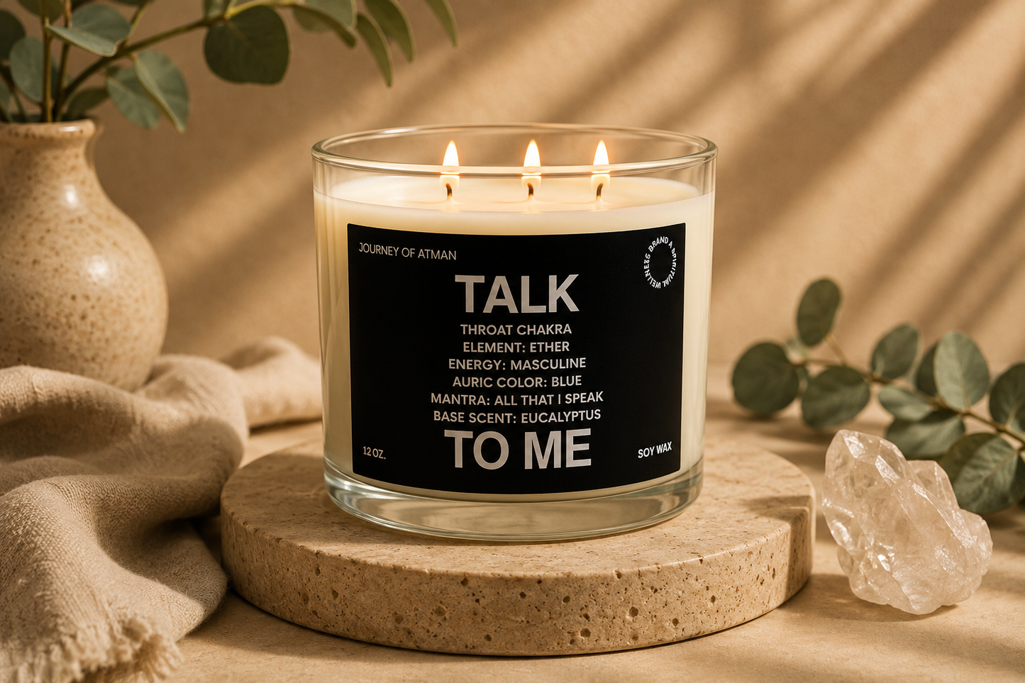 Talk to Me throat chakra candle by Journey of Atman displayed in a serene spa-inspired setting with eucalyptus accents, natural stone textures, and warm ambient lighting.
