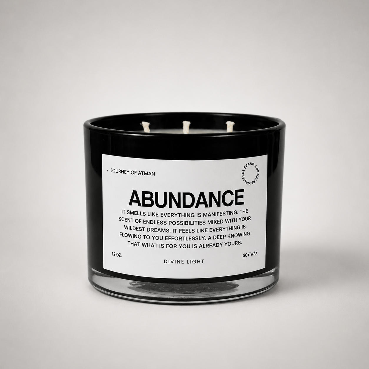 Abundance affirmation candle in black glass vessel with white label on clean white background for manifestation and intentional self-reflection.