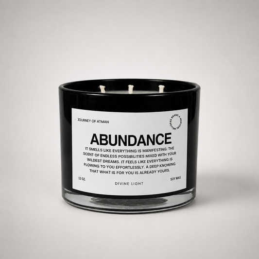 Abundance affirmation candle in black glass vessel with white label on clean white background for manifestation and intentional self-reflection.
