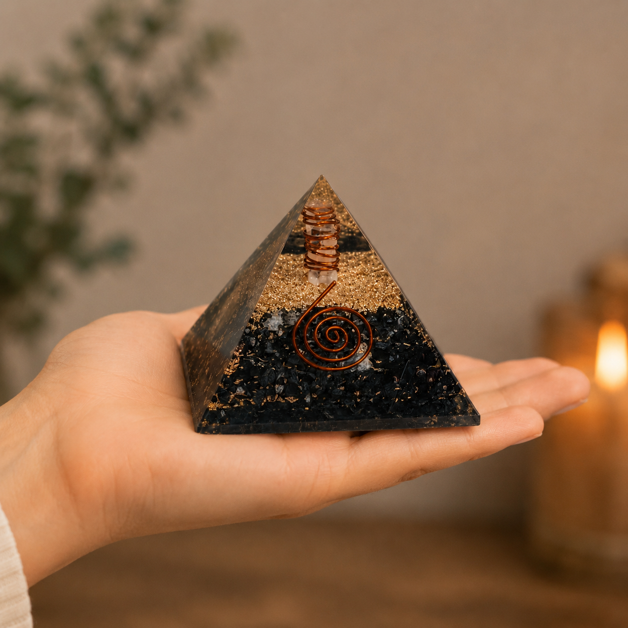 Hand holding black tourmaline orgonite pyramid featuring copper spiral and crystal layers for size reference.