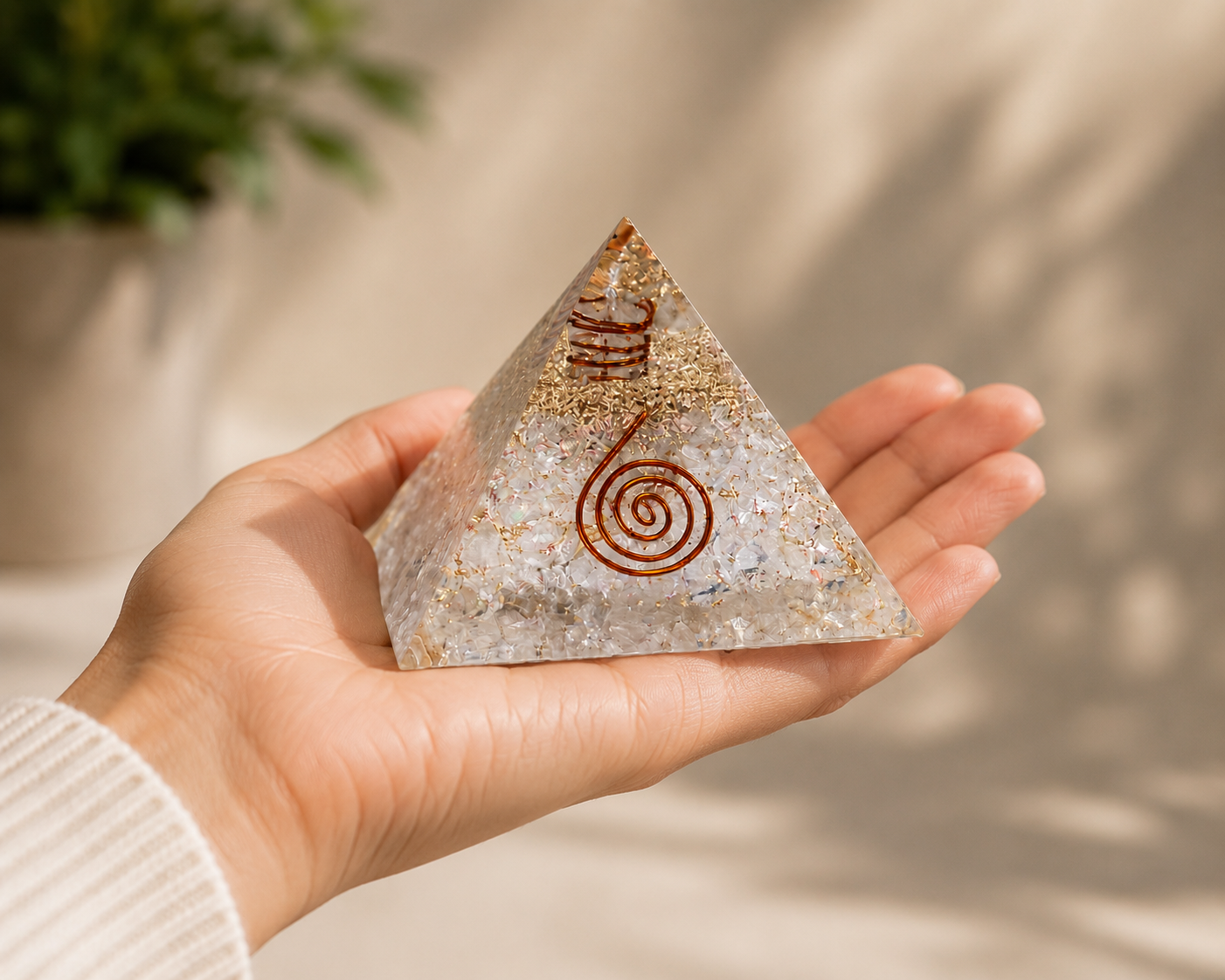 Hand holding clear quartz orgonite pyramid featuring copper spiral and crystal layers for size reference.