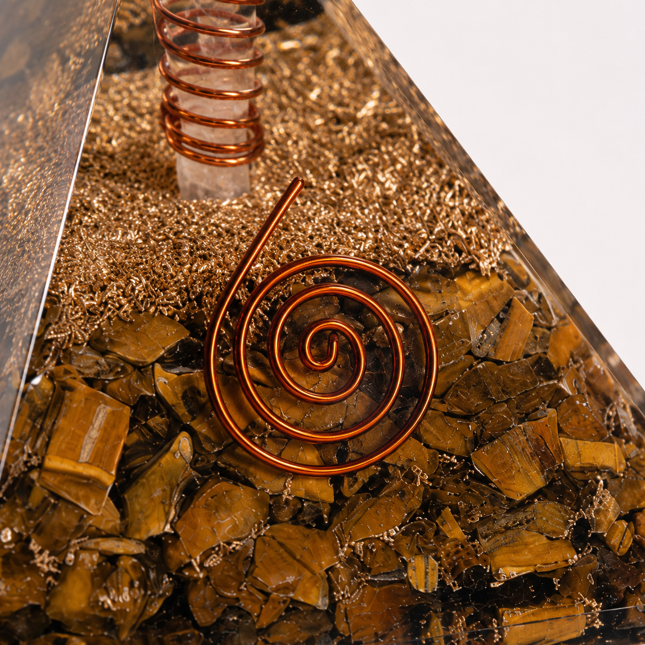 Close-up detail of tiger’s eye orgonite pyramid featuring crystal texture, copper coil, and resin craftsmanship.
